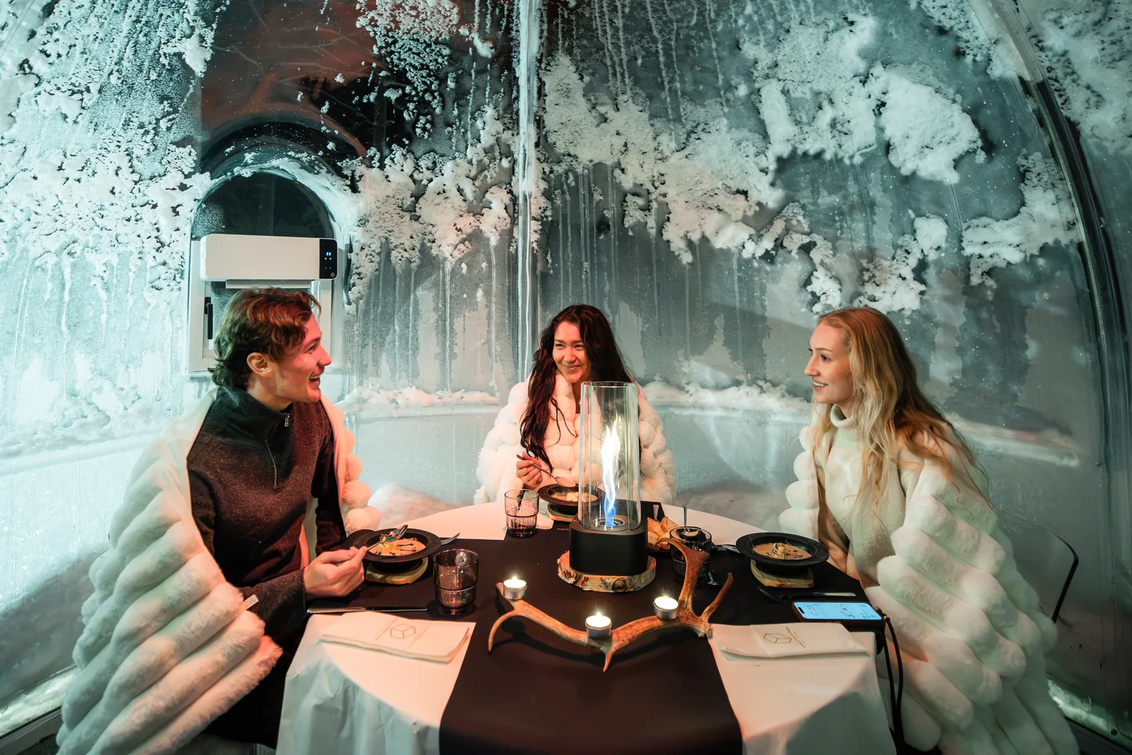 Hóspedes a jantar à luz das velas num iglu de vidro privado