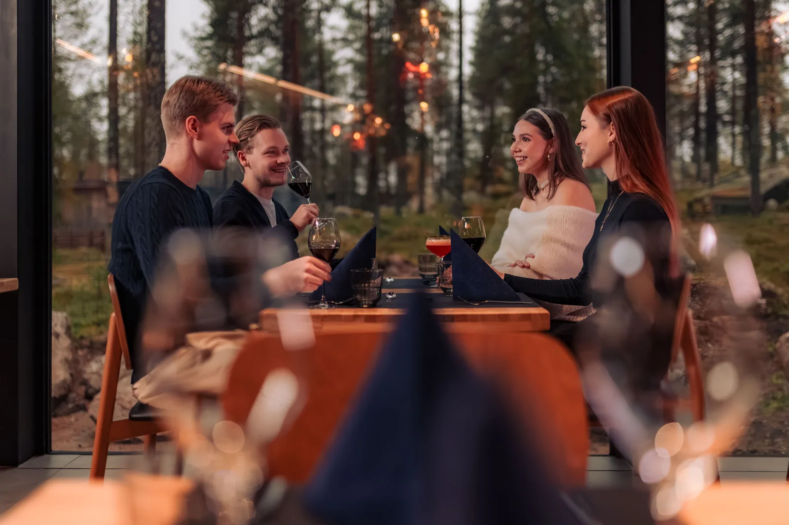 Amigos a partilhar jantar e vinho no restaurante com vista para a floresta
