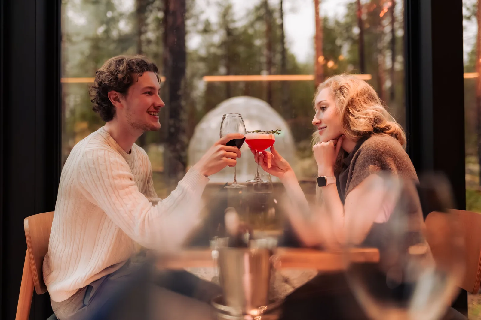 Casal a brindar durante o jantar no restaurante com vista para a floresta
