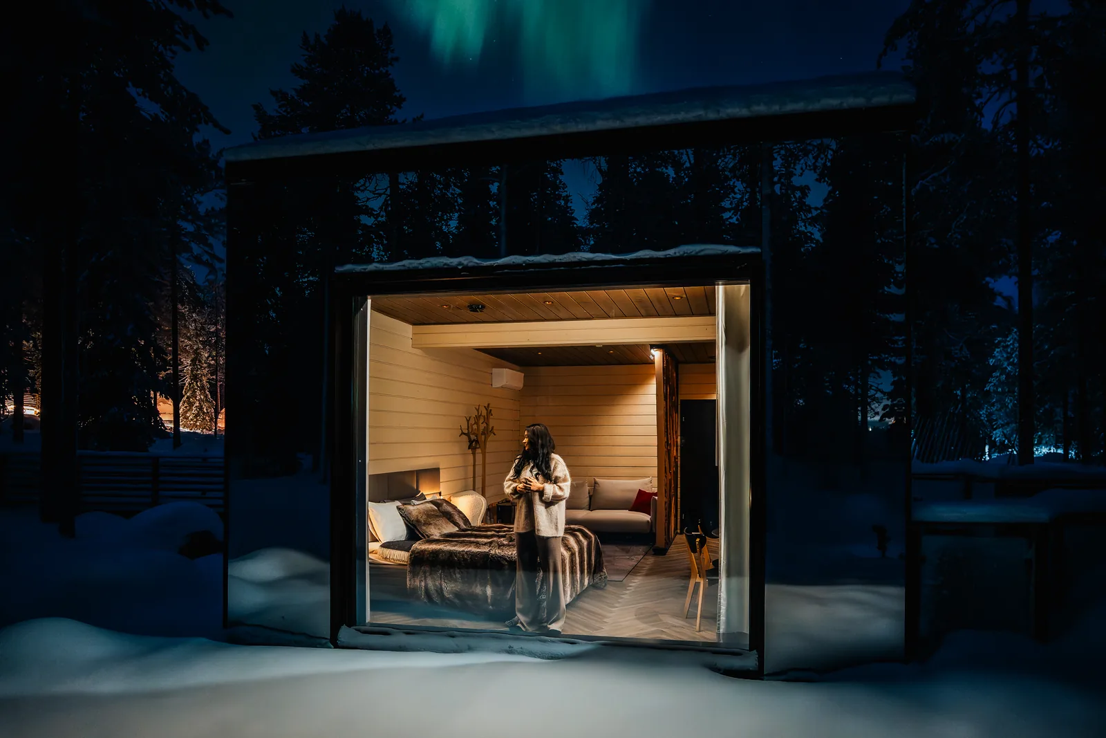 Paar in einer beleuchteten Invisible Suite unter Nordlichtern