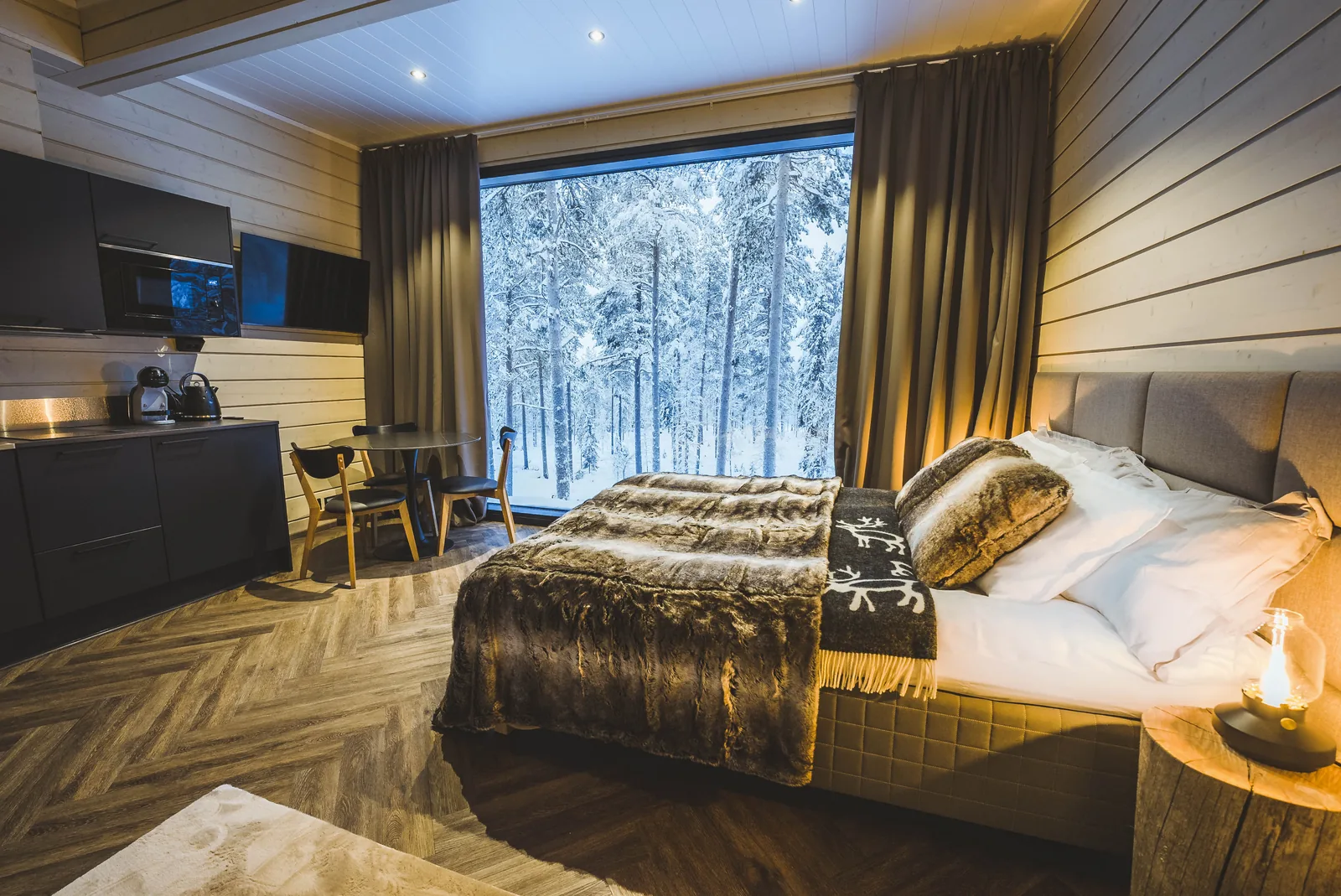 Schlafbereich und Küchenzeile der Invisible Suite mit Blick auf verschneiten Wald