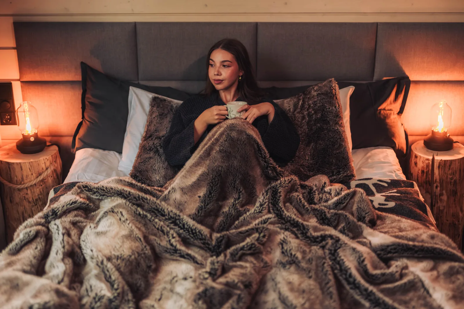 Gast entspannt im Bett einer Invisible Suite bei warmem Laternenlicht